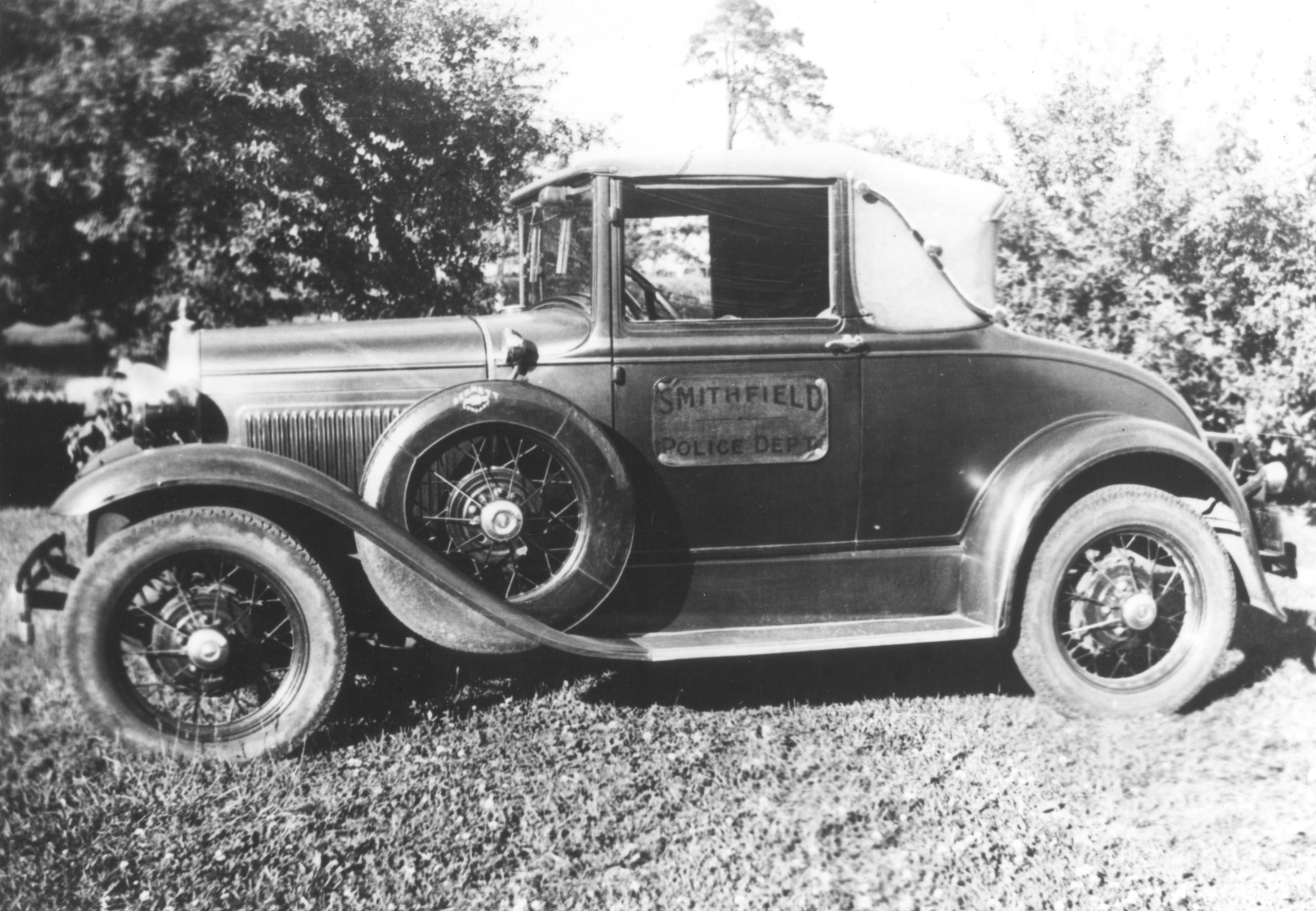 Black and white photo of a vintage Ford coupe with Smithfield Police Dept. lettering on the door.